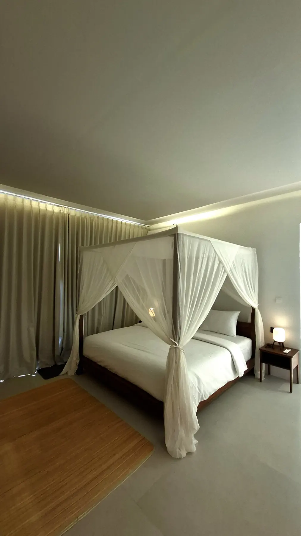 Ocean View Deluxe Bungalow bedroom at Maleo Moyo with a four-poster bed and white curtains