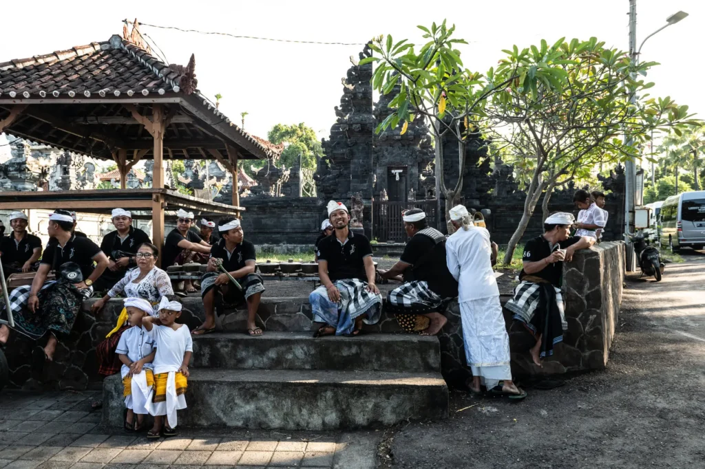 Un groupe d'hommes et d'enfants en tenue traditionnelle blanche et noire rassemblés près d'un temple en pierre sculptée