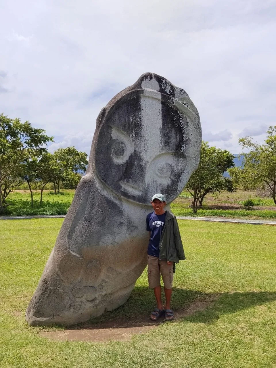 A guide beside the Palindo megalith in the Bada Valley, Sulawesi