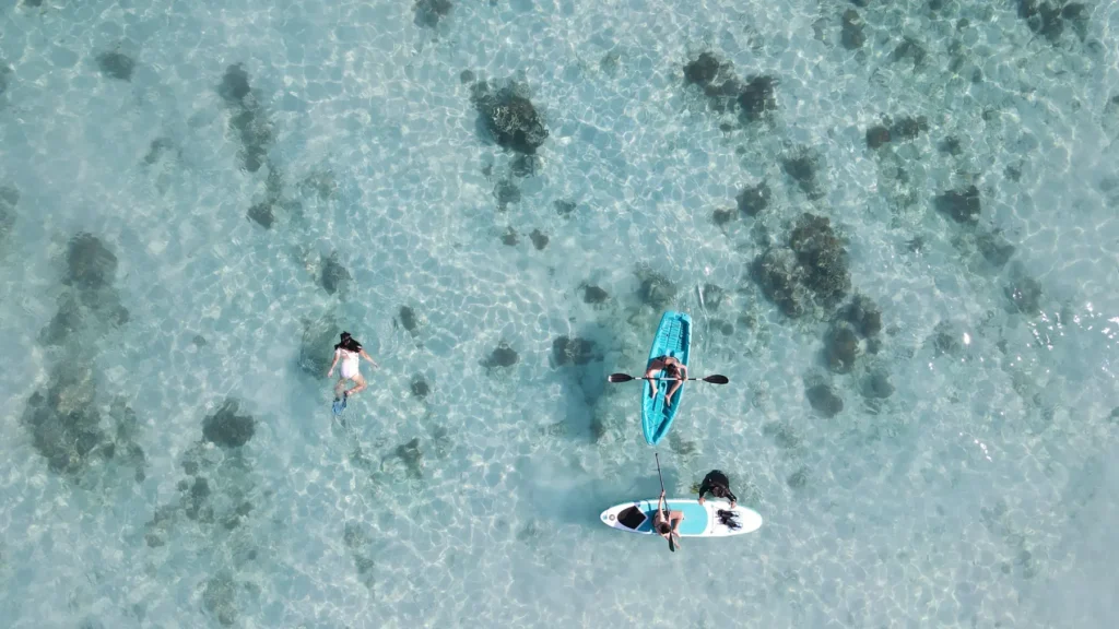 Guests paddleboarding and swimming over shallow reef from Dinara