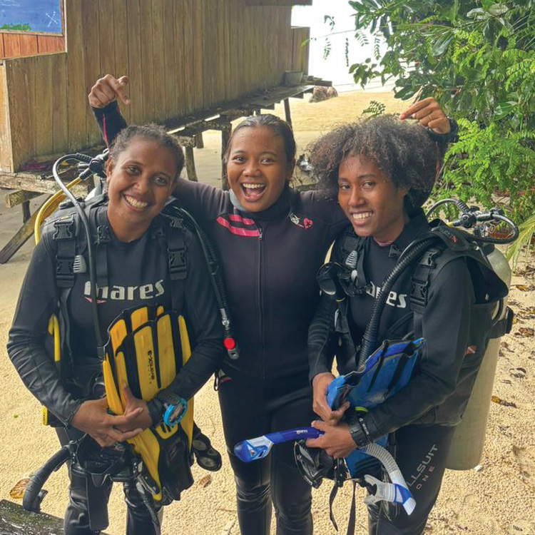 Three Expedition Biru dive trainees celebrating on the beach