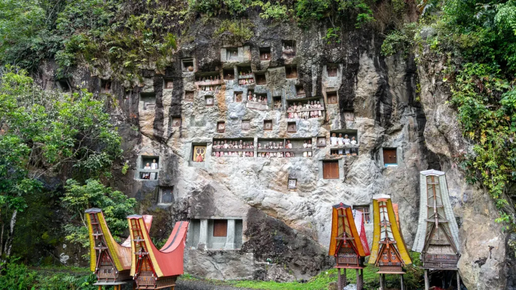 Tau-tau effigies watching from the cliff burial galleries at Lemo, Tana Toraja