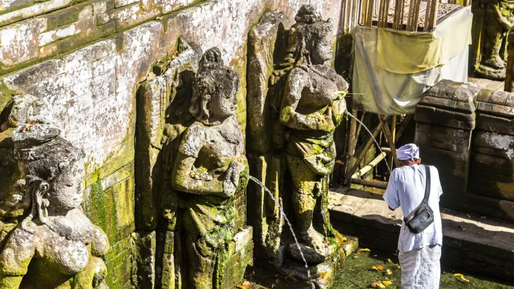 Stone statues pouring water into the sacred bathing pool at Goa Gajah