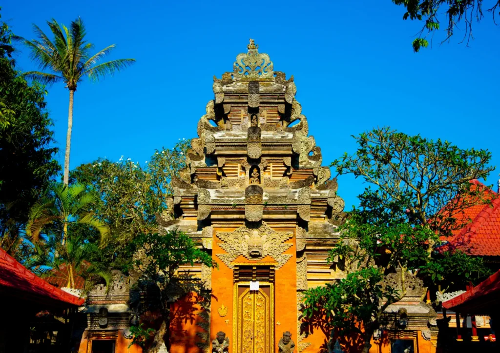Carved stone gateway of Ubud Palace under a blue sky