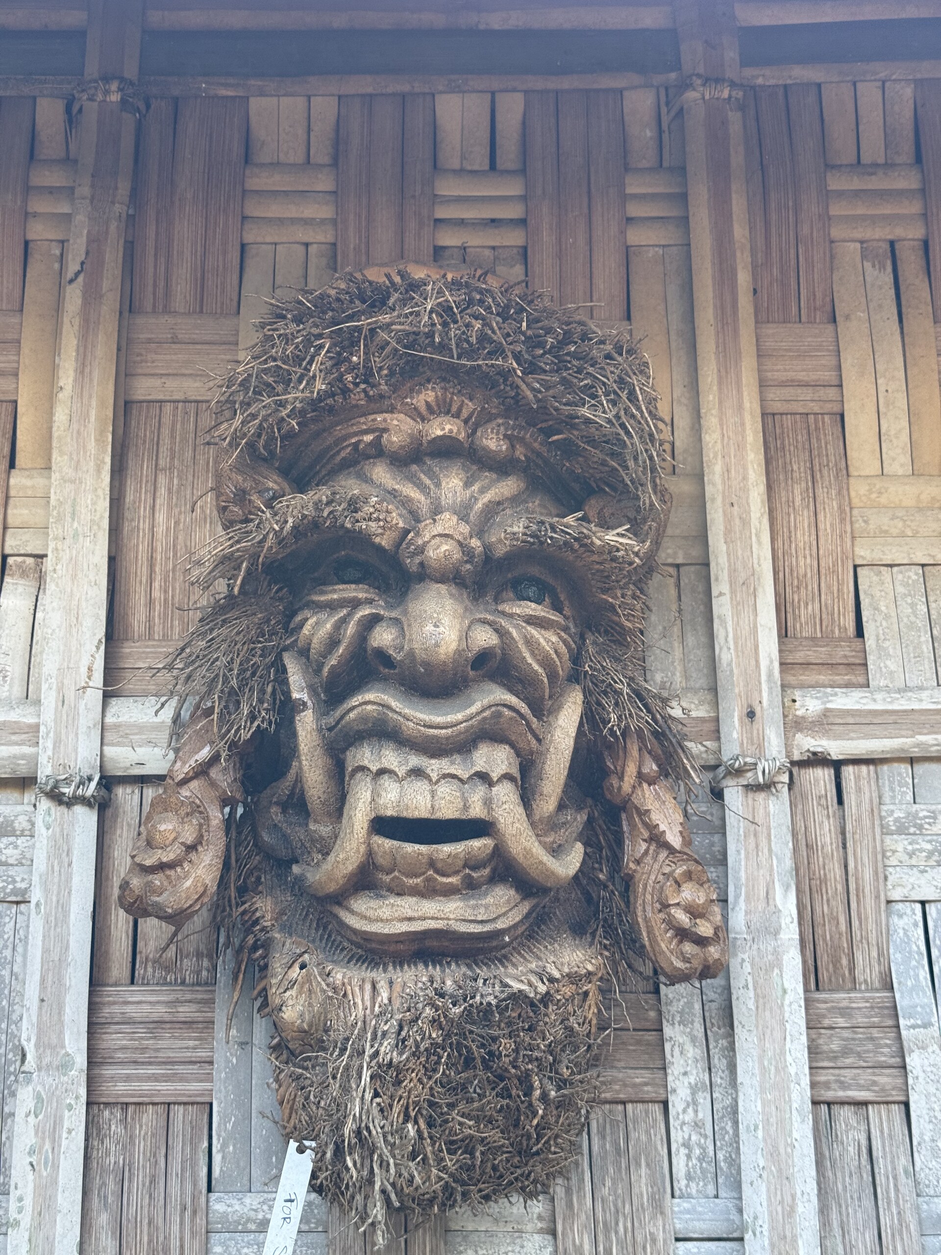 A large carved wooden face above the door of a Balinese building