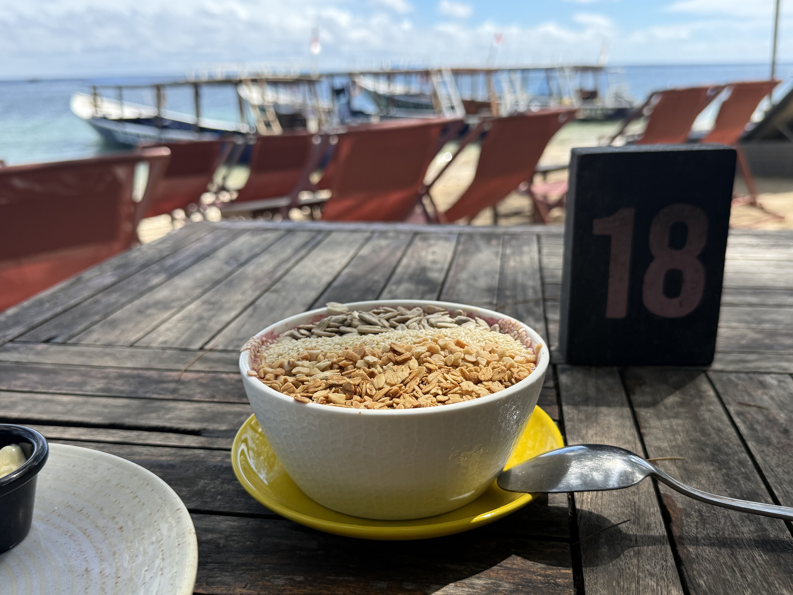 A breakfast bowl on a wooden table on a jetty over the water