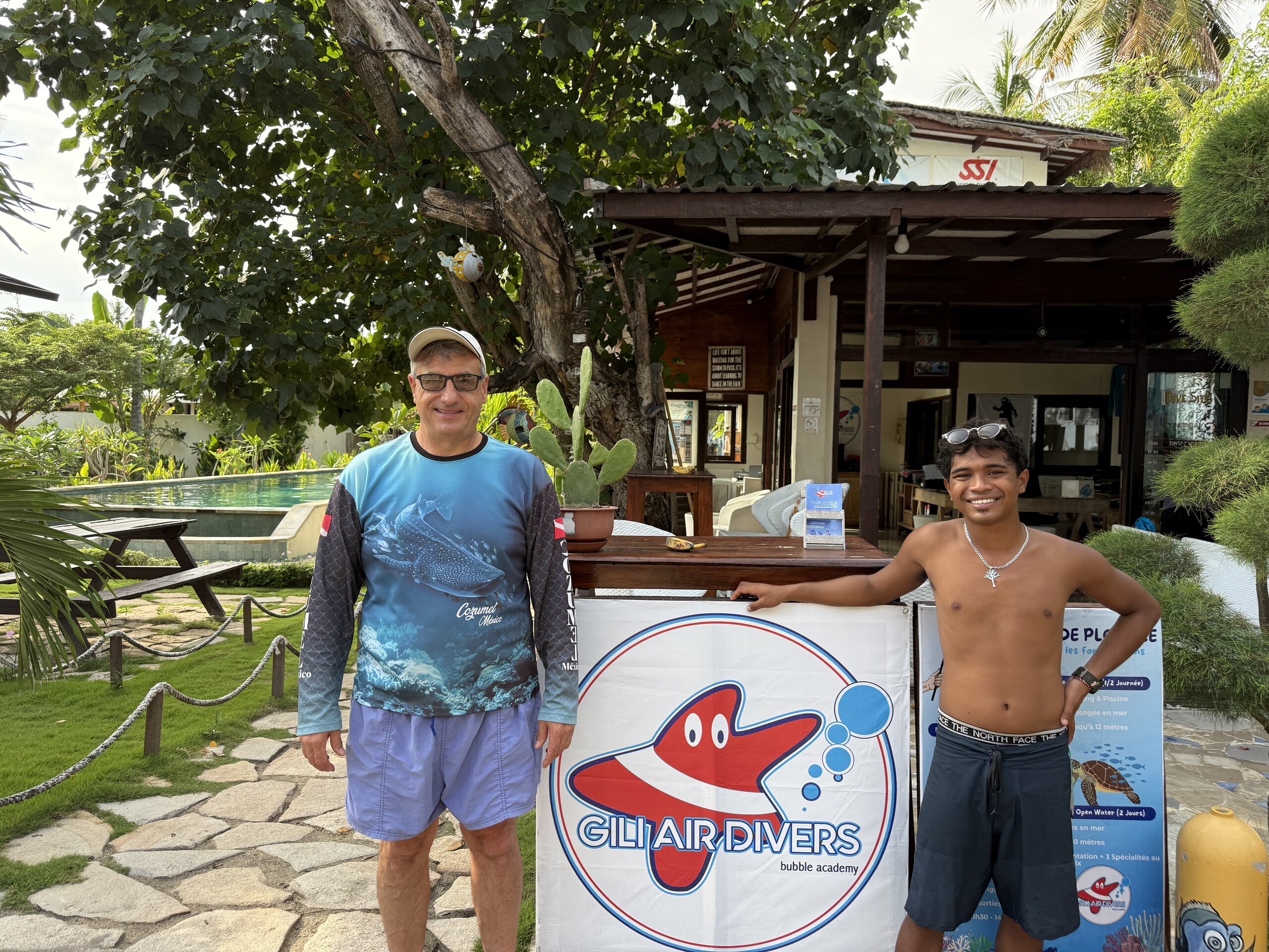 Dean with a member of the Gili Air Divers team holding the shop banner
