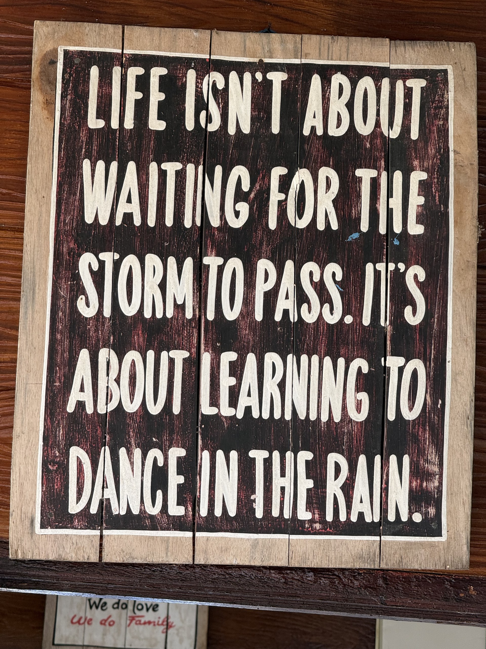 A wooden sign reading life isn't about waiting for the storm to pass, it's about learning to dance in the rain