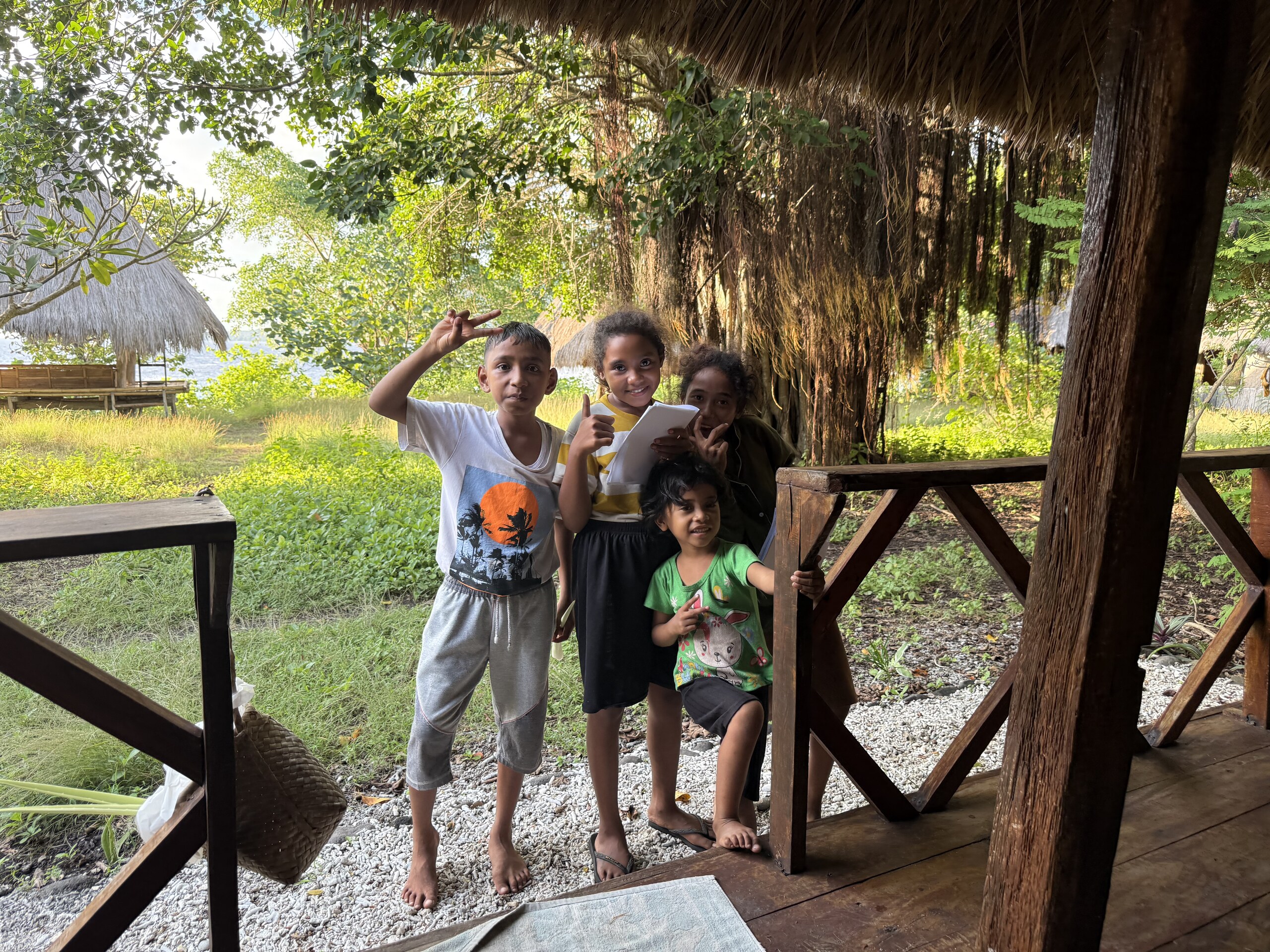 Children waving from the deck of a hut at Kepa