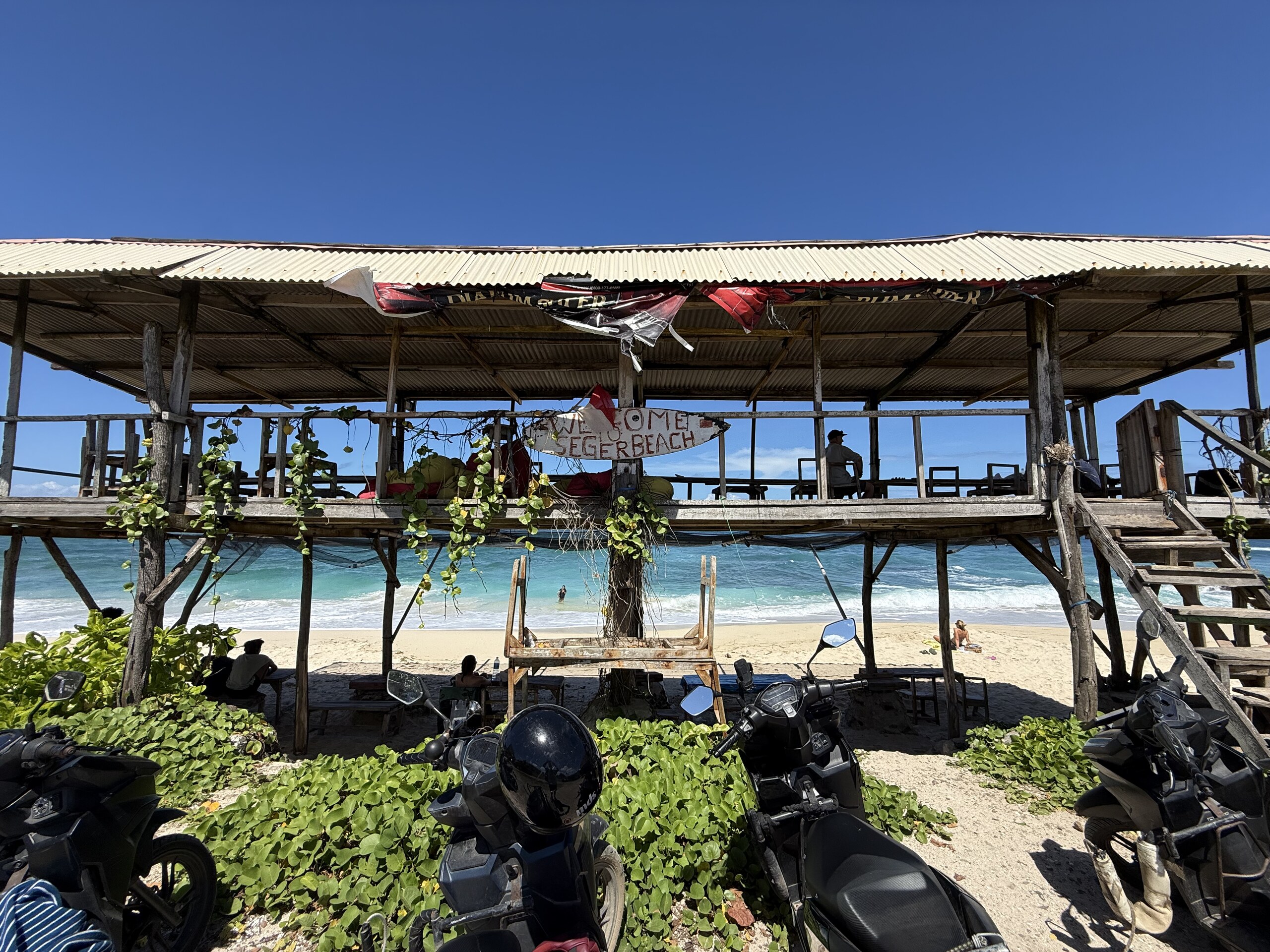A beachfront warung in Kuta, Lombok, with scooters parked outside