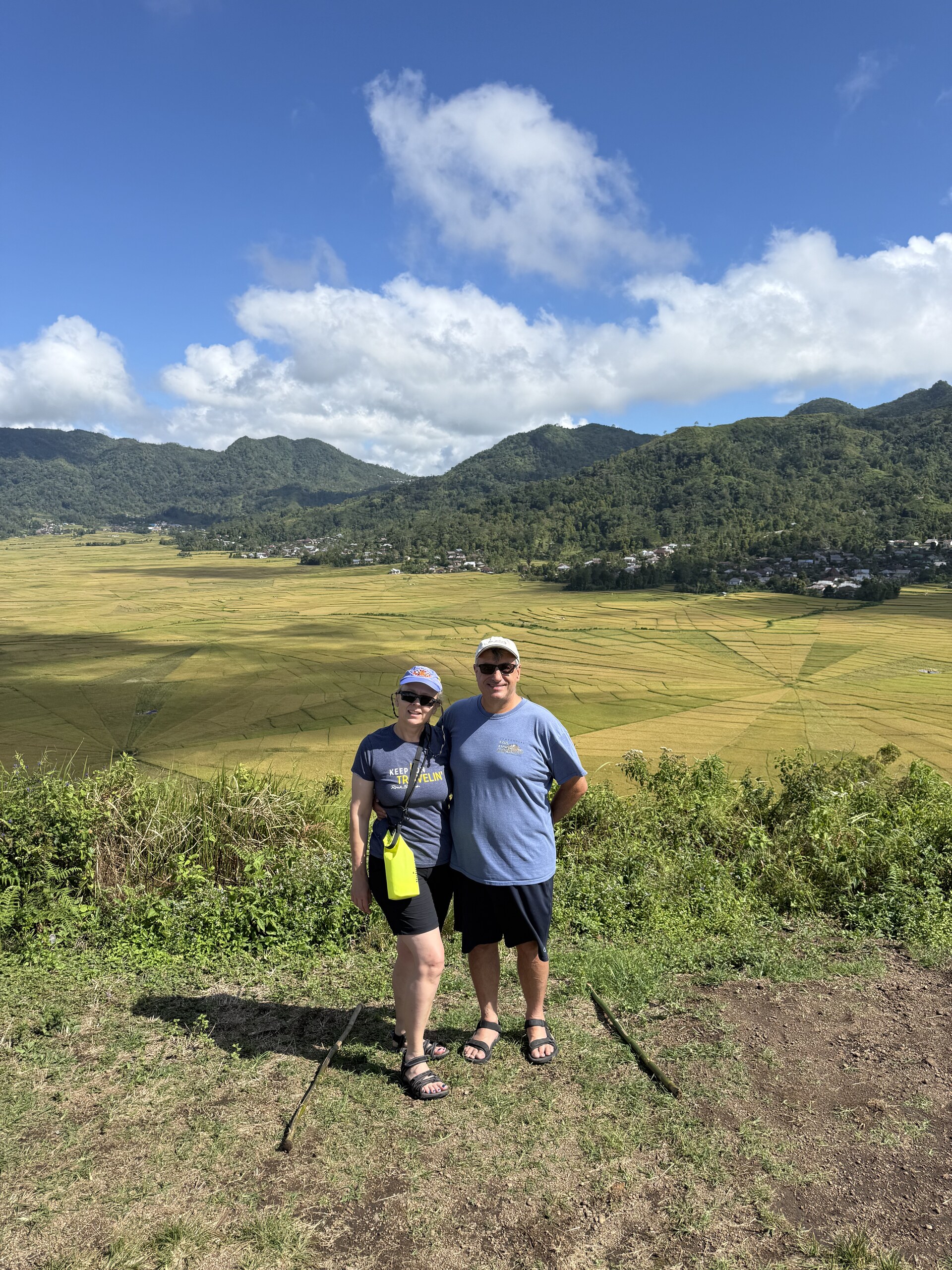Dean and Zita at a viewpoint above a green valley of farmland and hills