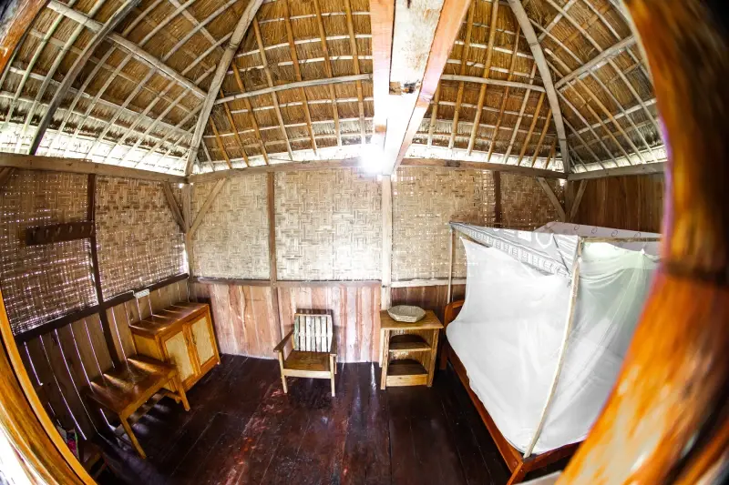 Inside a Standard bungalow, bamboo walls and a bed under a mosquito net