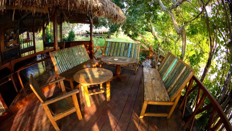 Wooden benches and low tables on the shaded terrace at La P'tite Kepa