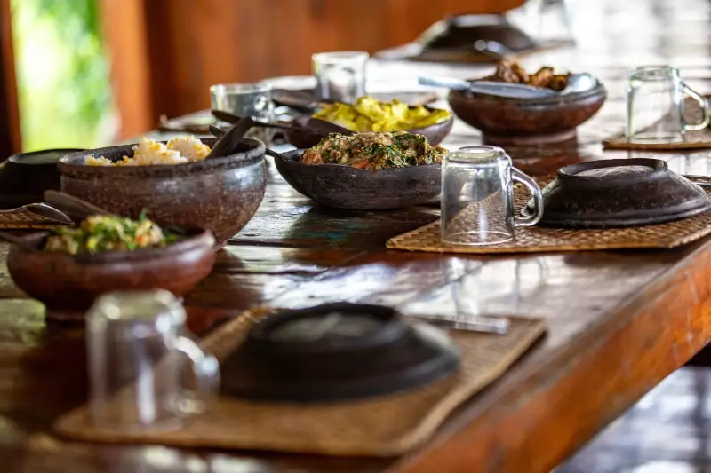Indonesian dishes served in clay bowls on the long wooden table at La P'tite Kepa