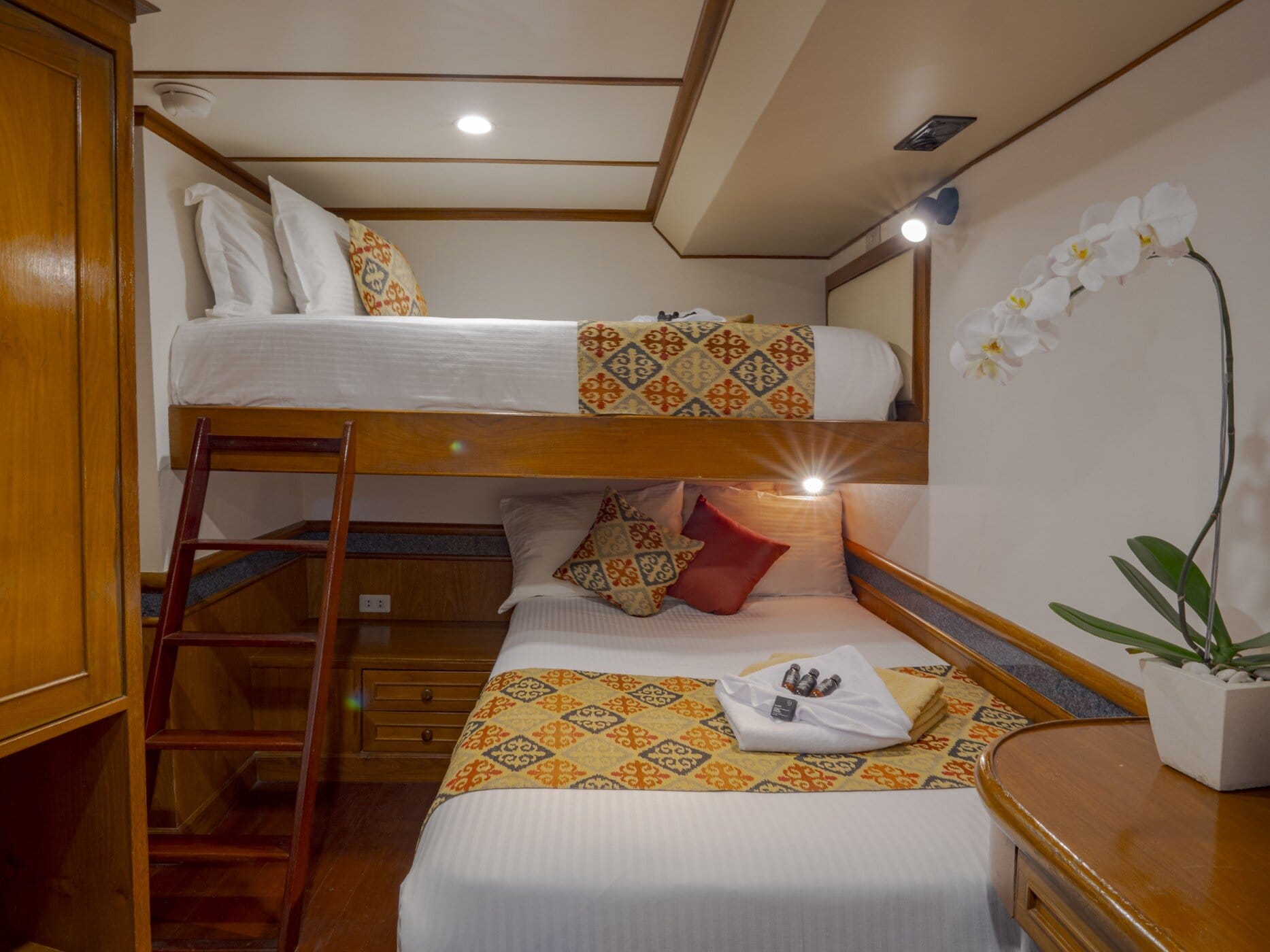 Lower deck cabin on the Mermaid I with a bunk over a single bed and a ladder to the upper bunk