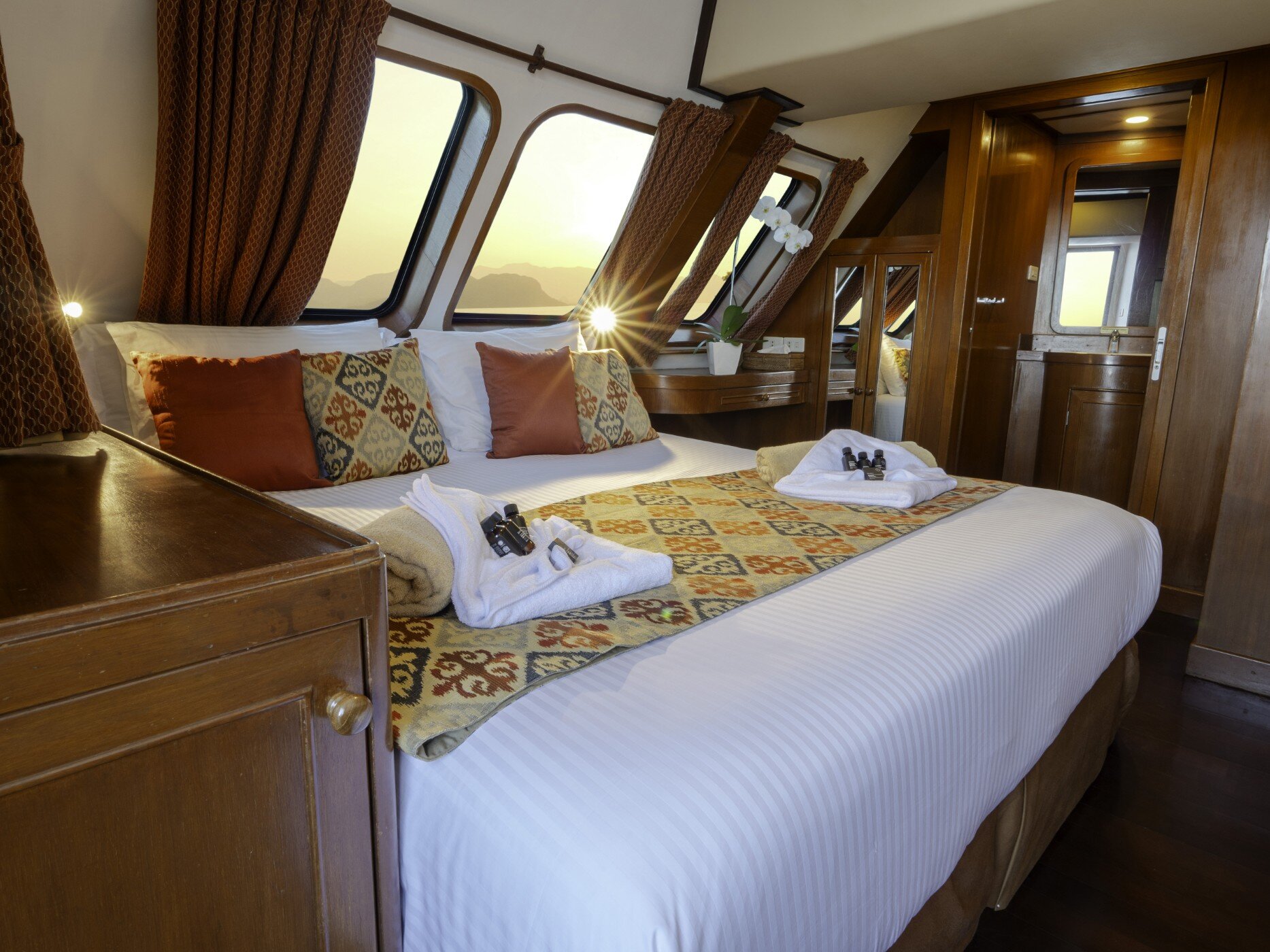 Master cabin on the Mermaid I with a king size bed, wood panelling and windows along one wall