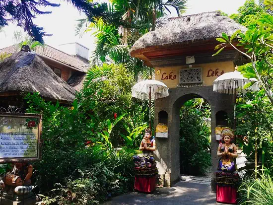 Thatched gateway with carved guardian statues at the entrance of Laka Leke
