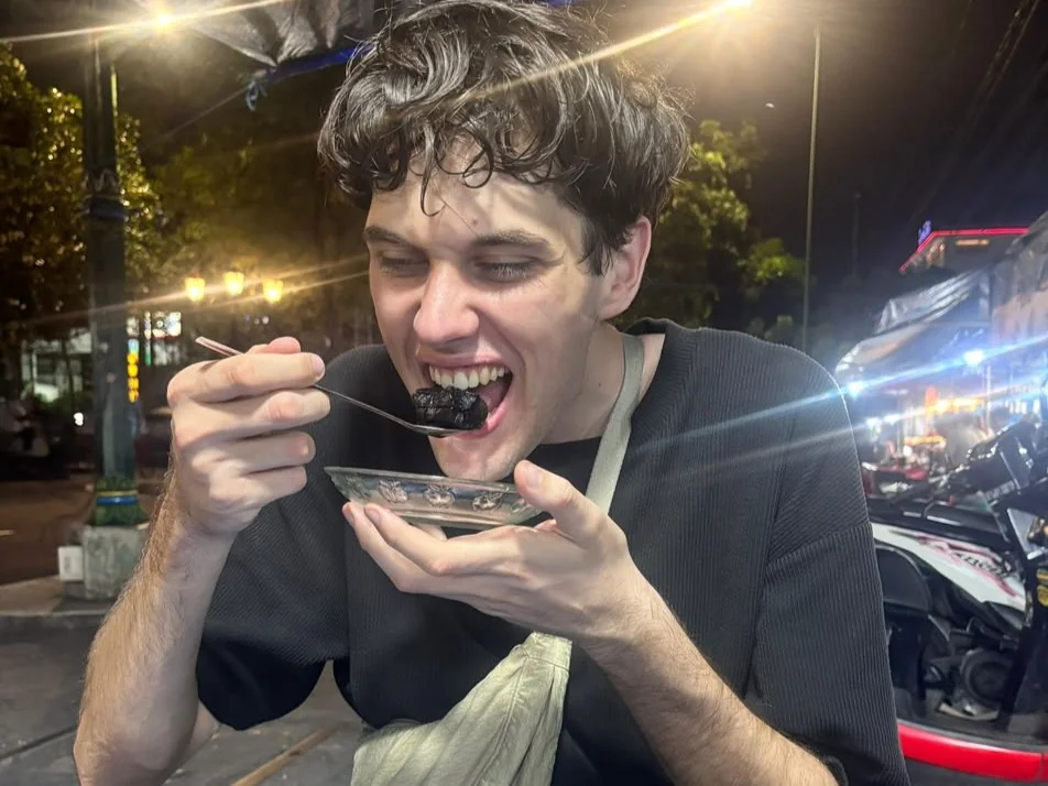 Man eating at an angkringan street stall at night near Tugu station
