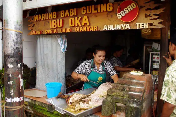 Cook carving roast pork at the counter of Babi Guling Ibu Oka