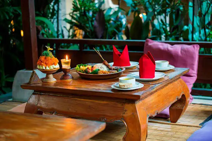Balinese dish served on a low table with candles and flowers at Café Wayan