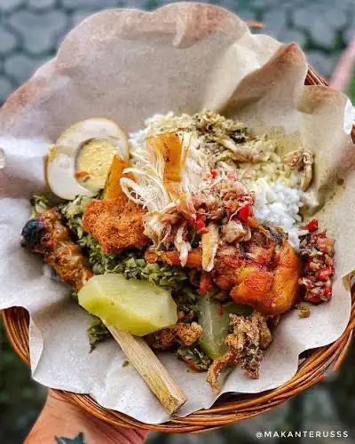 Nasi campur wrapped in paper with egg, sate and fried chicken