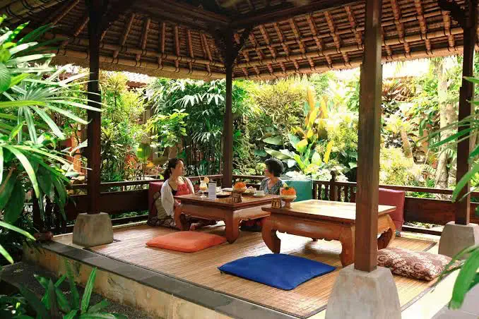 Low tables and cushions in an open pavilion surrounded by plants at Café Wayan