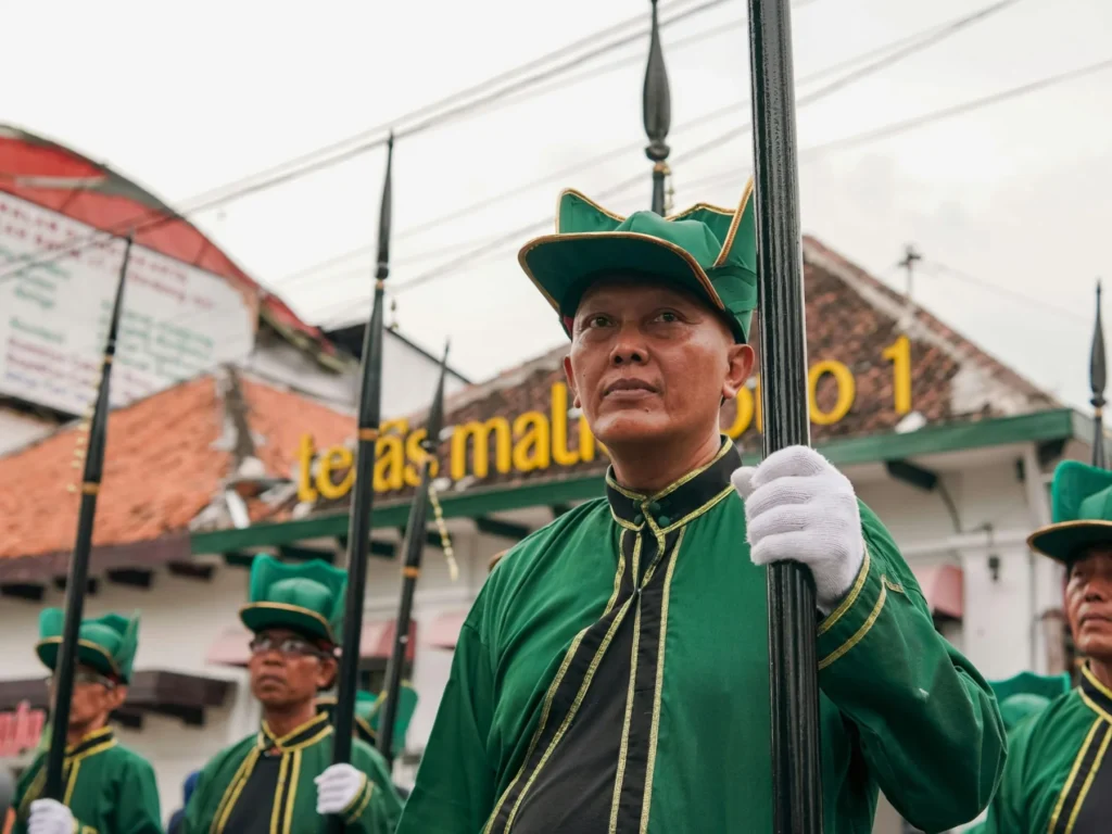 Palace guards in green uniforms carrying spears at the Keraton Yogyakarta