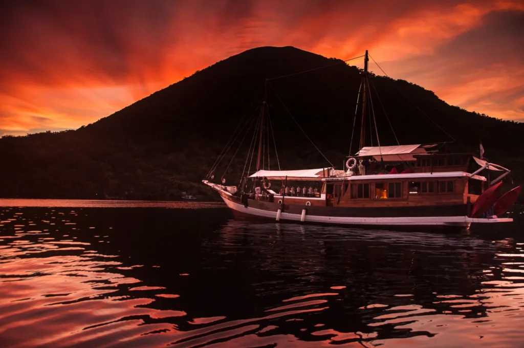 Phinisi liveaboard at sunset below the Gunung Api volcano at Banda Neira