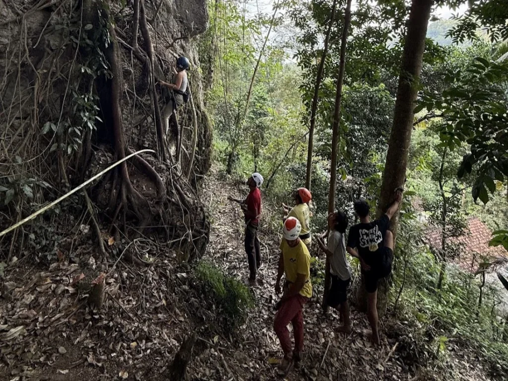 Climbers on a rock face in the forest with Turning Point Climbing Community