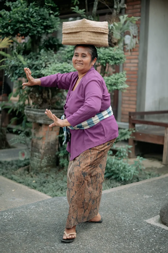 Une femme balinaise porte un panier en équilibre sur la tête dans un village d'Ubud