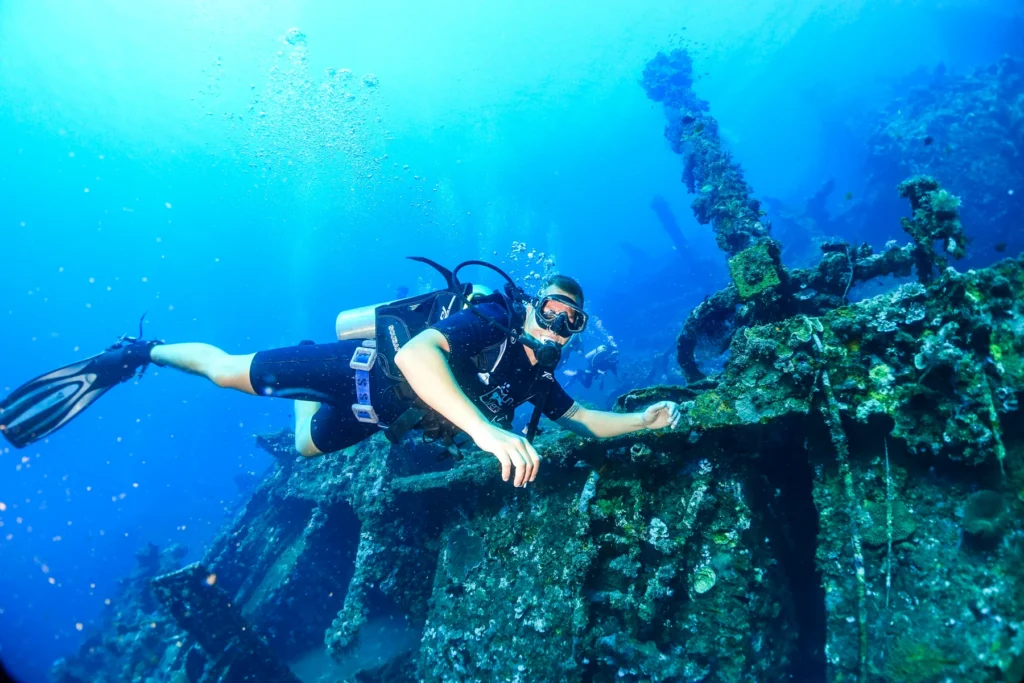 A diver swimming along the coral-covered USAT Liberty wreck in Tulamben, Bali