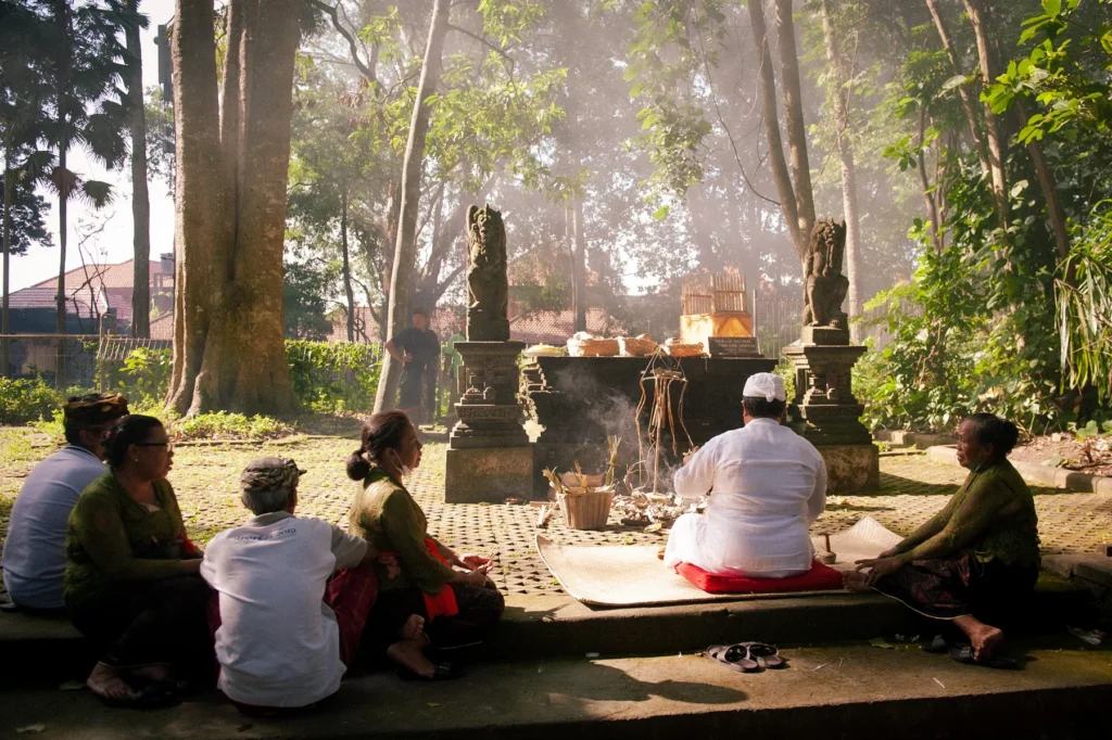 Worshippers in white seated before a smoking shrine during a ceremony in the Sacred Monkey Forest, Ubud