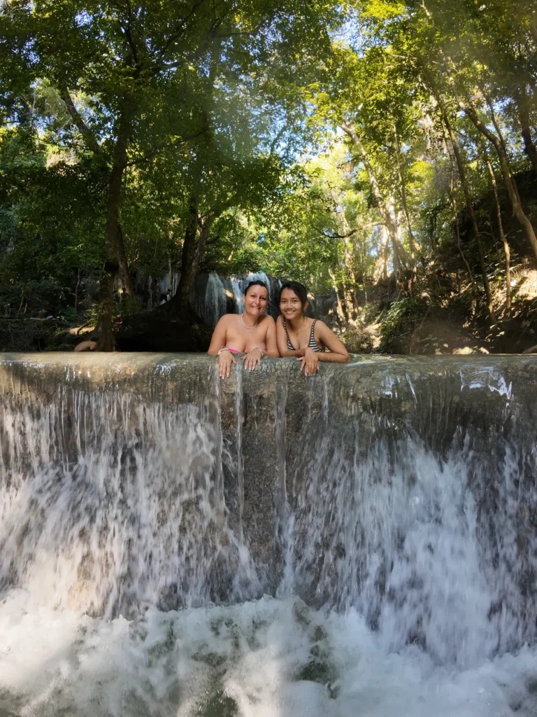 Two people swimming at the top of a cascade in the pools of Mata Jitu waterfall, Moyo Island