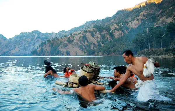 Hindu pilgrims wading into Segara Anak crater lake with offerings during Mulang Pekelem