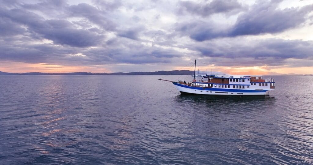 The Naga Biru phinisi at anchor on a calm sea at dusk