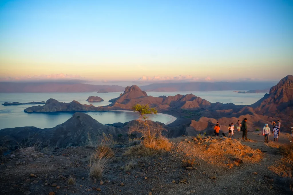 Hikers at the Padar Island viewpoint in Komodo National Park at dawn, looking over its three bays