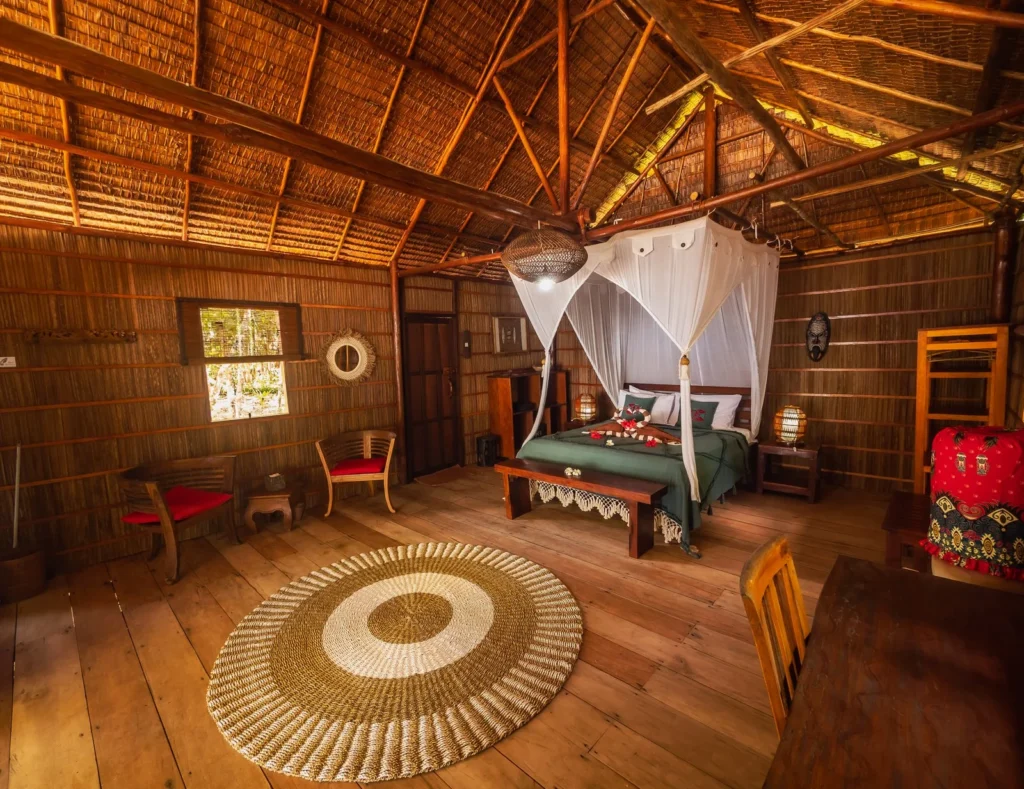 Deluxe Cottage bedroom with a mosquito net over the bed and wooden walls