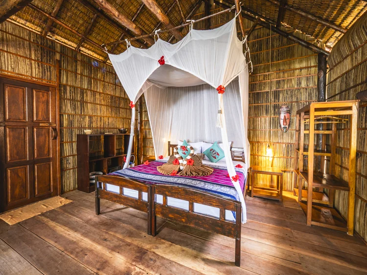 Raja Ampat Garden View Cottage bedroom with a mosquito net and wooden furniture