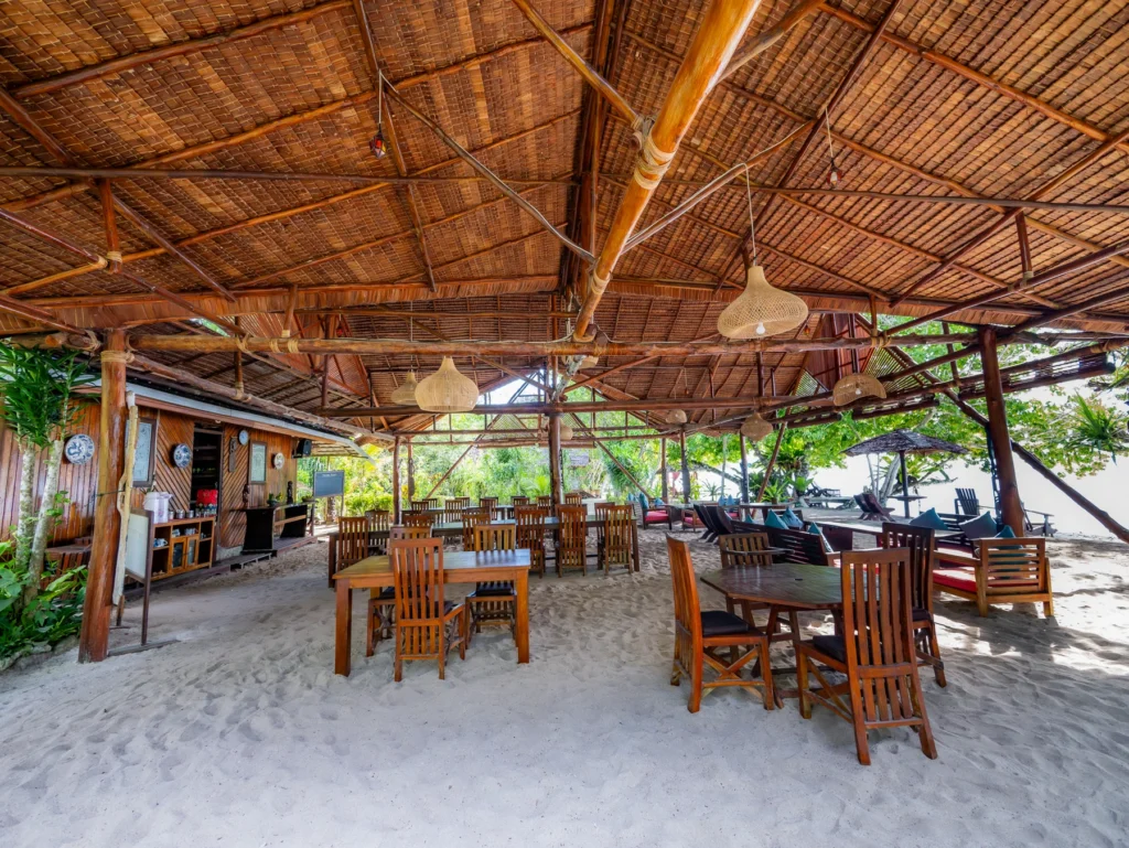 Open-air restaurant on the sand under a high thatched roof