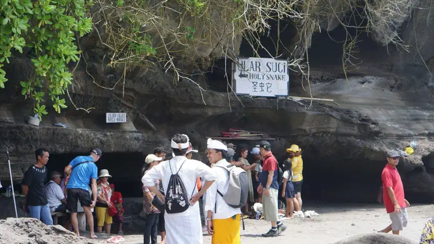 Visitors at the entrance of the holy snake cave at the foot of Tanah Lot