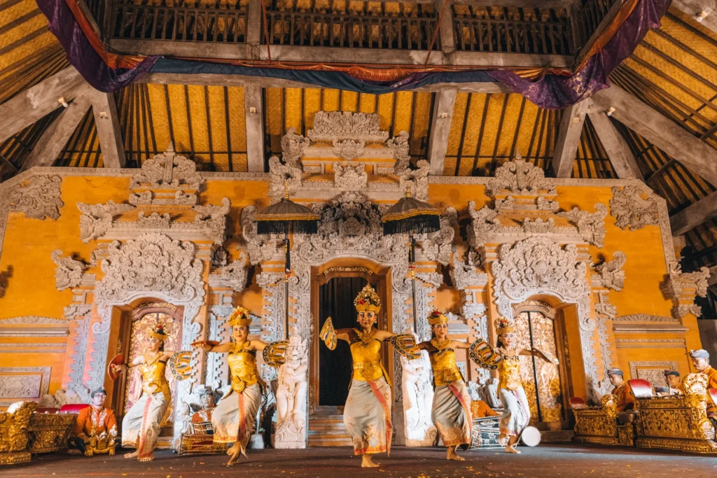 Dancers in gold costumes performing in front of the carved gateway of the Ubud Palace stage